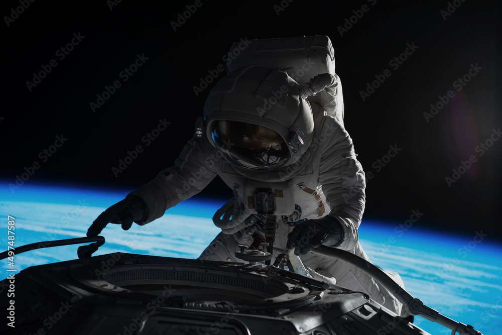 Wall mural female astronaut performing spacewalk, working on a outer part of a space craft