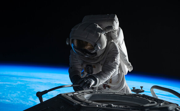 Female astronaut performing spacewalk, working on a outer part of a space craft - Powered by Adobe