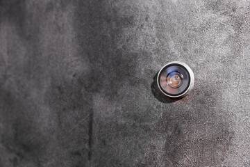 Door peephole on a dark gray metal door. Side view. copy space. - obrazy, fototapety, plakaty
