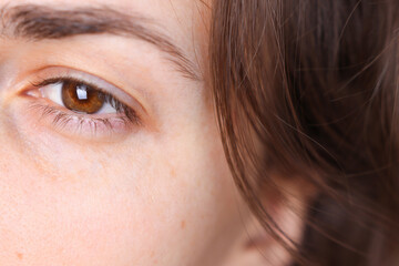 Close-up of a woman's face without makeup, natural beauty. A girl with brown eyes and hair looks away.