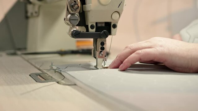 Close up process of embroidering diamond pattern on cowhide in atelier on step sewing machine. Creating unique interior design from personal brand. designer sits and sews on fabric.
