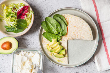 Cooking process for sandwich and ingredients. Process of prepare quesadilla with avocado, salmon, curd cheese and spinach. Trendy wrap hack. Step by step. Step 2