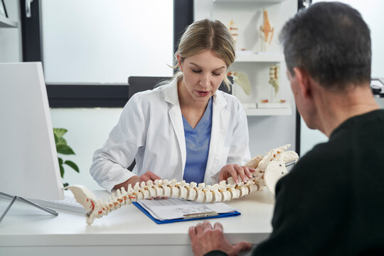 Caucasian female doctor talking with patient about his spine