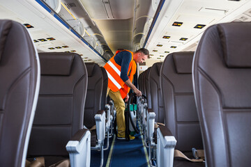 Aircraft cleaning service. Man cleaner working in airplane salon - 497490316