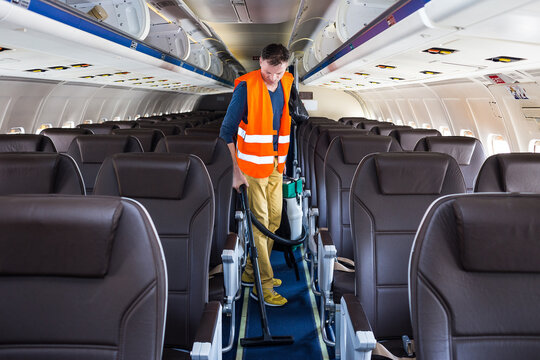 Aircraft cleaning service. Man cleaner working in airplane salon