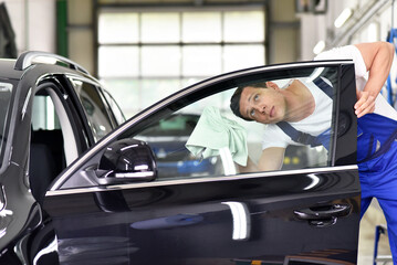 professional car wash - worker in a car dealership polishes the car paint