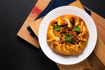 Food concept homemade rustic Ground Beef Pot Pie Galette in white plate on wooden board with copy space