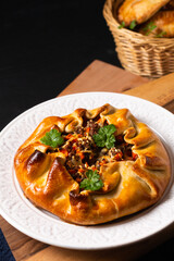 Food concept homemade rustic Ground Beef Pot Pie Galette in white plate on wooden board with copy space