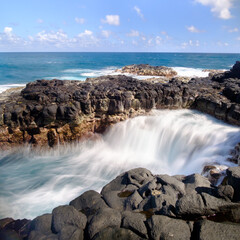 Long exposure of waves receding agains lava rocks