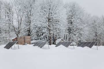 Solar panels in snowdrifts on the camping site in the winter forest