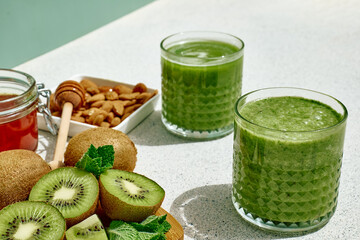 Fototapeta na wymiar Green smoothie with kiwi fruit in the glasses. Healthy organic drink. Nutrition and alkaline diet. Healthie eating vegetarian concept.