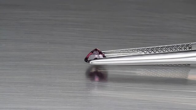 natural pink sapphire gemstone in the tweezers