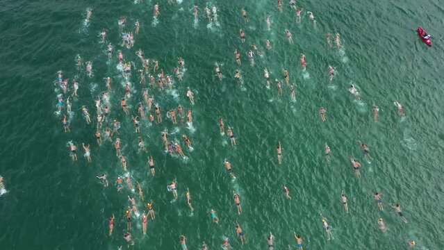 Aerial Drone Shot 4K of Triathlon Swimming Race. Ironman Competition. Traditional swimming marathon in Varna, Bulgaria. A huge group of people invades the water. Start swimming in the sea or ocean.