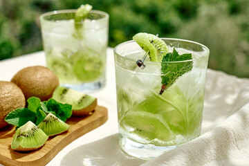 Summer cold drink and beverages. Lemonade with kiwi, mint  and ice in glass. Rinfreshment unalcolic cocktail. Selective focus.