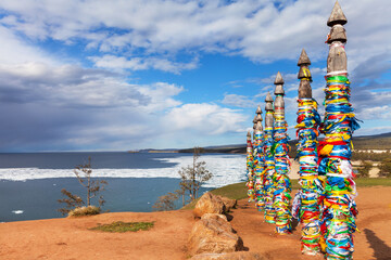 Baikal Lake. Olkhon Island in springtime. Ice drift in Sarayskiy Bay. Sacred place near Khuzhir village.  On famous Cape Burhan, tourists tie colorful ribbons to poles and make wishes. Travel concept