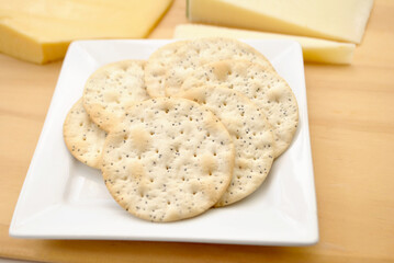 Close-Up of Sesame Crackers with Gourmet Cheeses in the Background	