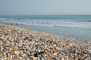 bank of pebbles with the sea and beach in the background	

