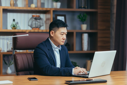 Concentrated businessman working on laptop in classic office, looking at monitor screen