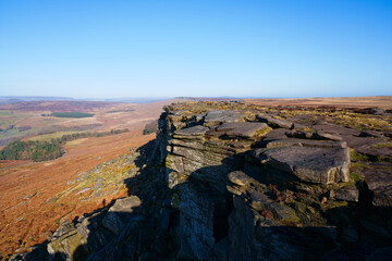 Fototapeta na wymiar Along the gritstone face of Stanage Edge under a cloudless blue sky.