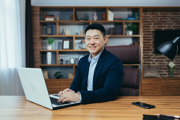 Portrait of a successful Asian businessman, man working in the office sitting at the table, looking...
