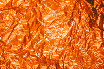 Fototapeta premium Full frame creased shiny metal foil sheet in trich golden red color. Background or backdrop