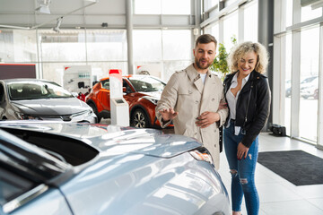 Fototapeta na wymiar Happy couple choosing cars in dealership