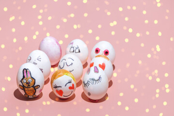 Easter eggs painted by children with different painted faces are placed on a pink background. Emotions of joy, love and shyness and Pink Bunny. Bright lights, Copy Space.