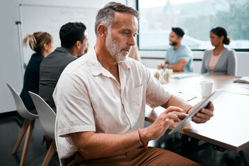 Making sure he misses nothing. Cropped shot of a handsome mature businessman attending a meeting in the boardroom with his colleagues in the background.
