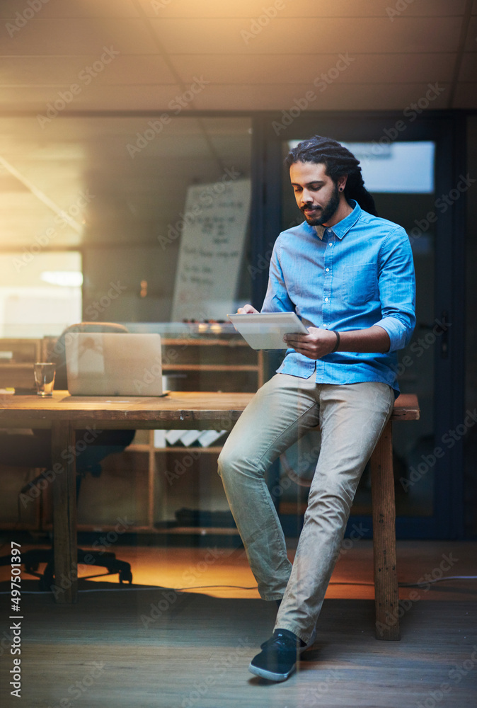 Poster browsing around for some ideas online. shot of a young designer working late on a digital tablet in 