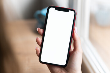 Young man hands holding mobile smart phone with mockup white blank display, empty screen at home. Shopping, delivery apps, social media applications ads,  close up view.