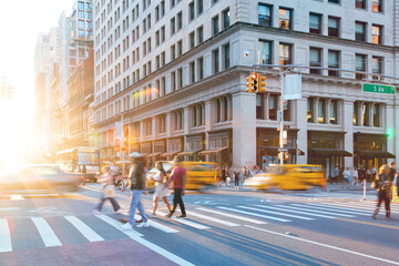 People and cars at the busy intersection of 23rd Street and 5th Avenue in New York City with sunlight background