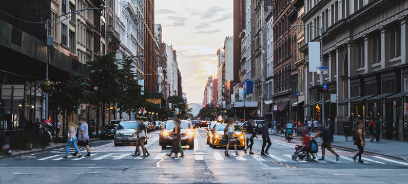 Busy street scene with crowds of people walking across an intersection on Fifth Avenue in New York City