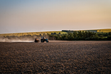 Obraz na płótnie Canvas tractor sows in the evening field