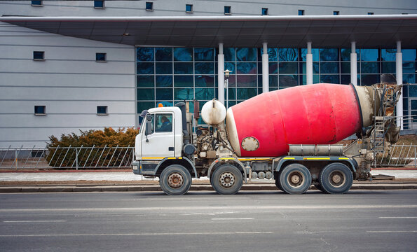 Cement mixer truck delivering concrete to construction site. Concrete mixer delivers concrete, truck moving on city road. Mixer truck transporting cement. Heavy machinery deliver cement