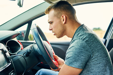 Whats making that funny sound. Shot of a young man having troubles with his car while driving.