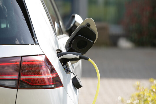 plug in adapter in car charge battery of electric car next to a charging station with yellow cable to refuel with renewable energy