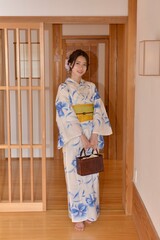 日本家屋の廊下でポーズをとる浴衣を着た若く美しい女性	