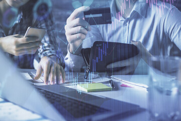 Double exposure of man and woman on-line shopping holding a credit card and forex graph hologram drawing. Stock market E-commerce pay on-line concept.