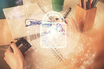 Double exposure of woman on-line shopping holding a credit card and Lock hologram drawing. Security E-commerce concept.