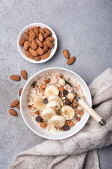 Healthy breakfast with oatmeal, nuts, banana and chocolate drops