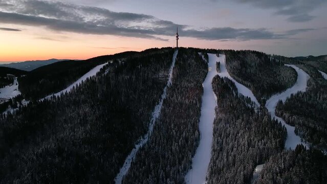 4K Aerial winter sunrise or sunset view of Rhodope Mountains and Snezhanka tower near resort of Pamporovo, Smolyan Region, Bulgaria