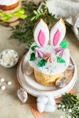 Happy Easter. Traditional Russian or Ukrainian Easter cake Kulich with meringue icing, candy shaped eggs and cookies. Holiday concept.