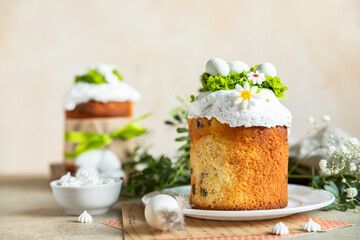 Happy Easter. Traditional Russian or Ukrainian Easter cake Kulich with meringue icing, candy shaped eggs and flowers. Holiday concept.