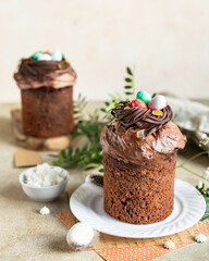 Traditional Orthodox Easter chocolate sweet bread or cake with chocolate nests and eggs on ceramic plate. Easter composition with chocolate Kulich, eggs and flowers.