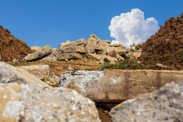 A view of the rubble of concrete blocks obtained from demolition of an old road is laid near a mound.