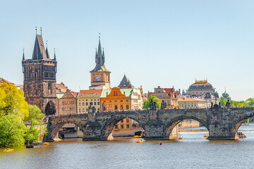 Fototapeta na wymiar View over magnificent Vltava river with tour boats, tourists and famous Charles Bridge and walking embarkment in historical downtown of Prague, Czech Republic at blue sunset summer sky.