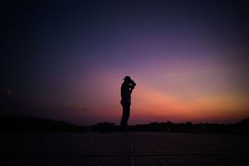 Photographer's silhouette standing still and taking pictures throught the horizon