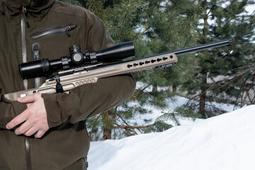 A sniper rifle with an optical sight in man`s hands winter day