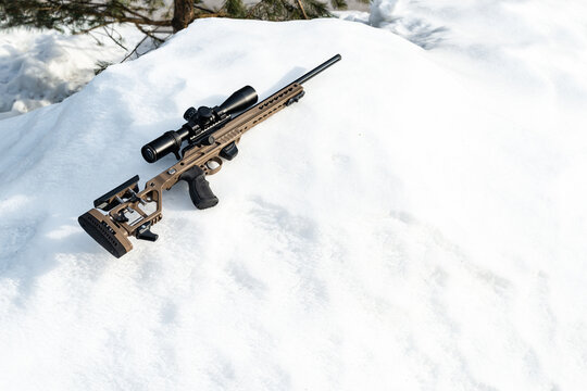 A sniper rifle with an optical sight on snow in winter day