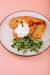 A classic dish of Ukrainian is a Kiev cutlet on a white plate on a pink background